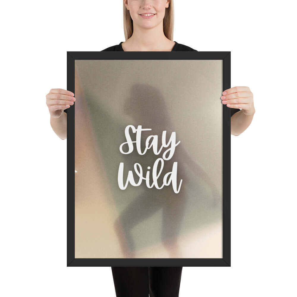 Framed 'Stay Wild' art print held by a person, featuring soft colors and a dreamy background, ideal for home and office decor.